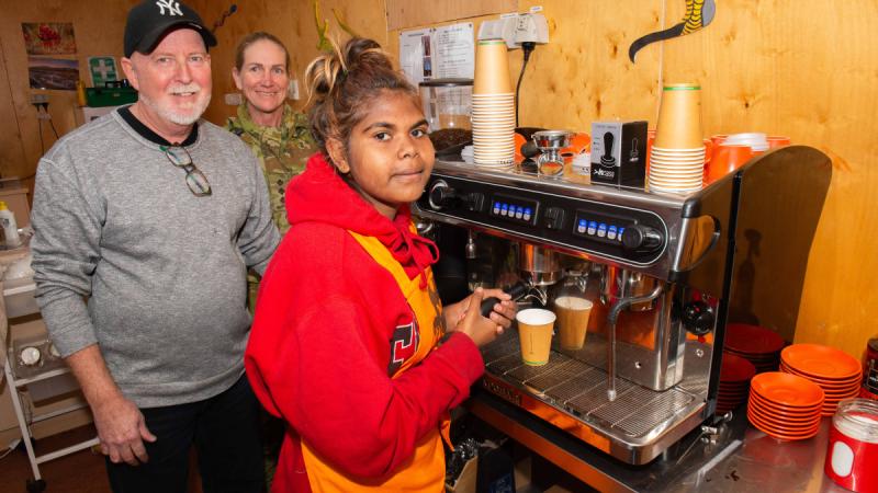 Robert Mergard helps Captain Debra Johnson and a TAFE SA student refine their espresso coffee making skills using the coffee machine and beans he supplied to the Amata community during the 2024 Army Aboriginal Community Assistance Programme in Amata, South Australia. 