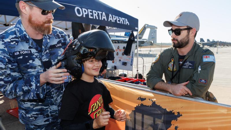 Angus, from the Starlight Children’s Foundation, tries on an F-35A helmet with the help of Corporal Daniel Lake, a 3 Squadron life support fitter, at the Pitch Black open day at RAAF Base Darwin. 