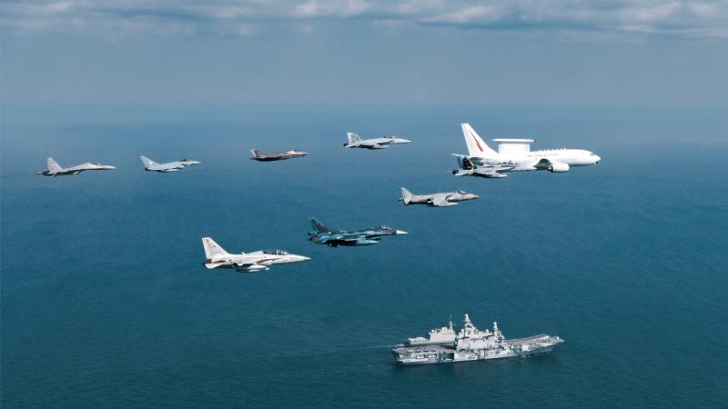 A Royal Australian Air Force E-7A Wedgetail leads a formation of aircraft past the Italian Navy aircraft carrier ITS Cavour during Exercise Pitch Black 2024.