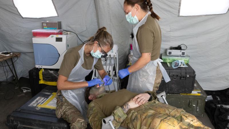 Royal Navy dental surgeon Lieutenant Grace Smalley (left) and dental nurse Able Rate Jamie Shand (right) from 40 Commando perform a dental examination on an Australian Army soldier at the Role 2 Basic medical treatment facility during Exercise Predator's Run at the Bradshaw Field Training Area.