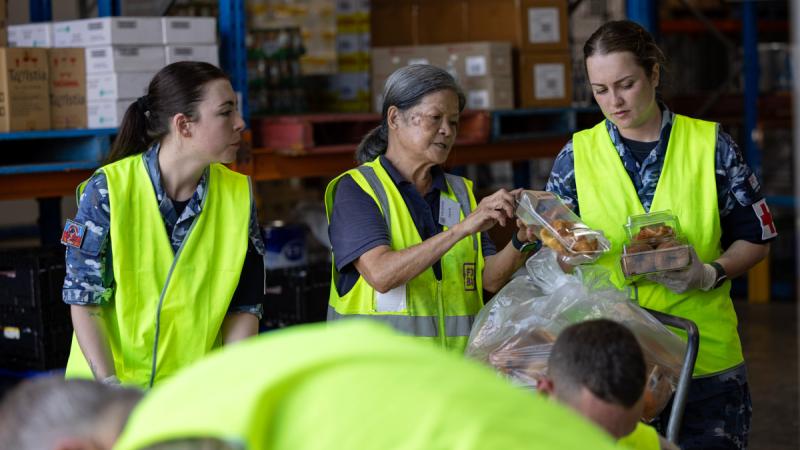 RAAF aviators Aircraftwoman Tandia Simmons, left, and Flying Officer Anneka Zerbes help Foodbank SA & NT volunteer Joyce sort bakery items during a community engagement activity. 
