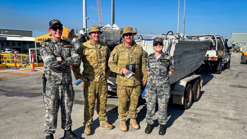 Navy sailors from HMAS Perth, Chief Petty Officer Bosun Glen Nipperess (left) and Lieutenant Commander Gemma Casserly, return a recovered craft to its owner, Australian Army soldier Warrant Officer Class Two Carl Stanley (centre right) at HMAS Coonawarra.