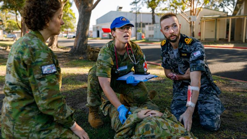 Medical officer, Flight Lieutenant Bronte Leonard (centre) from 2 Expeditionary Health Squadron assesses a patient with assistance from the walking wounded during a simulated mass-casualty event at RAAF Base Williamtown. 