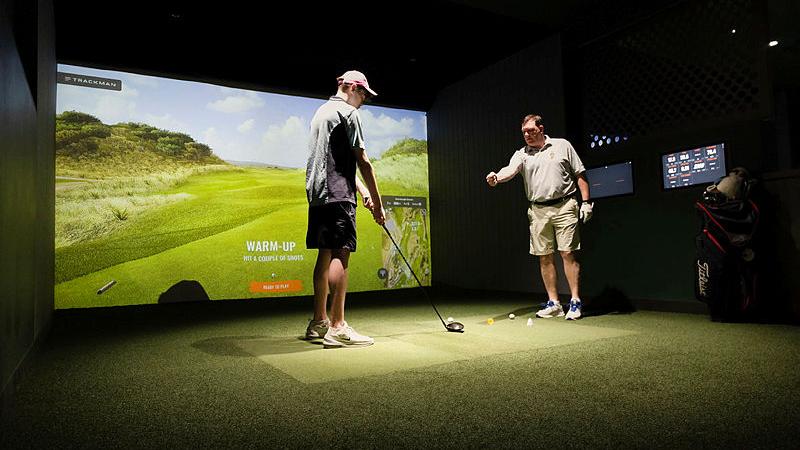 A member of the Royal Australian Navy golf club coaches a Sydney Secondary College, Leichhardt Campus student during a golf activity at GolfSpace.