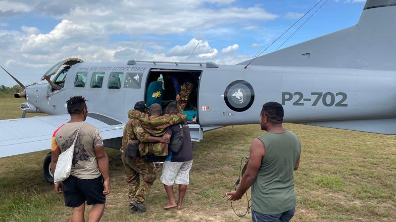 Infantry soldiers from 1st Battalion, Royal Pacific Islands Regiment, and civilians assist a snake bite casualty in to a PNG Defence Force Air Element PAC750-XL aircraft. 