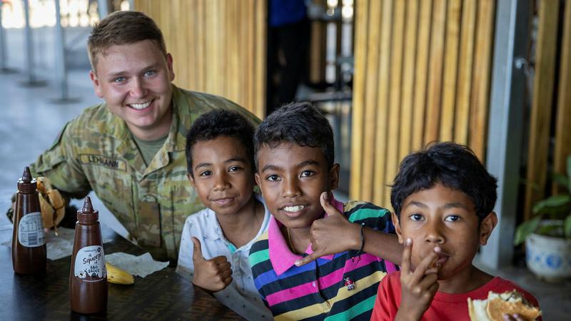  A soldier from the 1st Combat Engineer Regiment enjoys a barbeque with children at the "Green Kitchen" behind the Presidential Palace in Dili, Timor-Leste, as part of Exercise Hari'i Hamutuk.