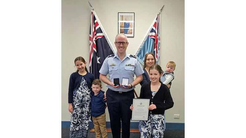 Sergeant Daniel McDowell holds his award and poses with his wife, daughters and sons at RAAF Base Wagga, NSW.