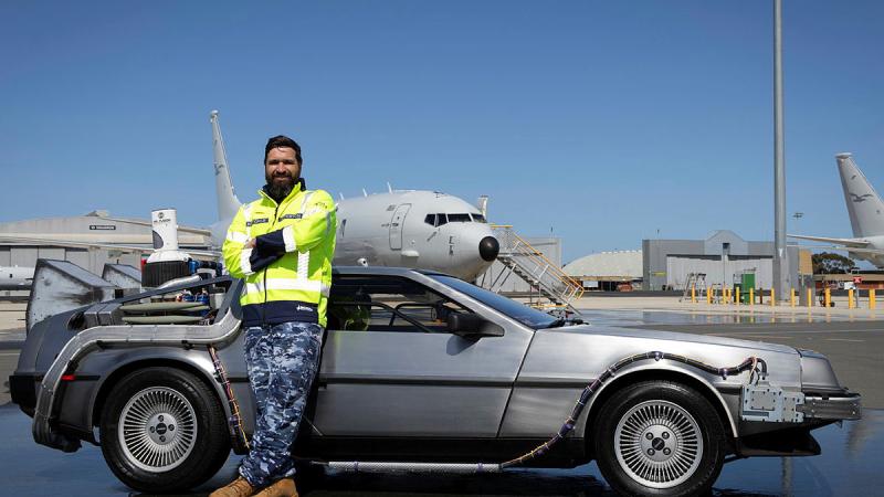 Sergeant Nicholas Atterton stands with a DMC DeLorean replica time machine car during its visit to the RAAF Base Edinburgh. 
