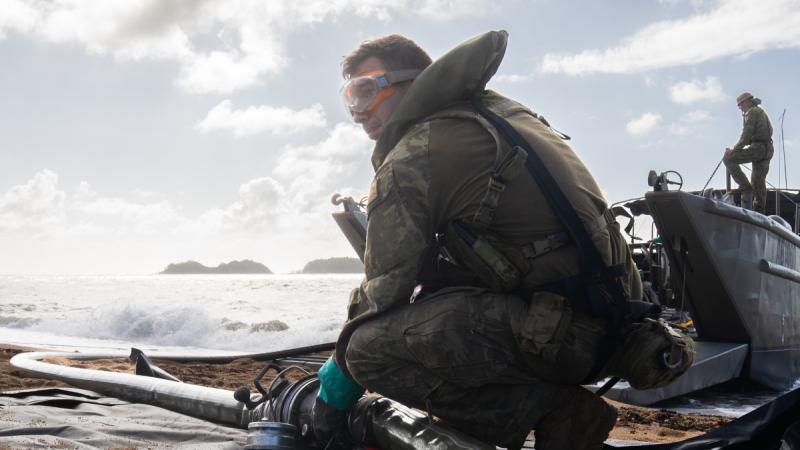An Army petroleum operator trainee preparing to transport fuel from a Landing Craft Mechanized, Mark 8 to the Beach Storage Area in the vicinity of Cowley Beach Training Area, Queensland. 