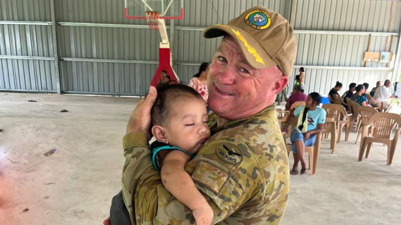 Pacific Partnership deputy mission commander, Wing Commander Scott Minchin holds a child during the mission in the Pacific.