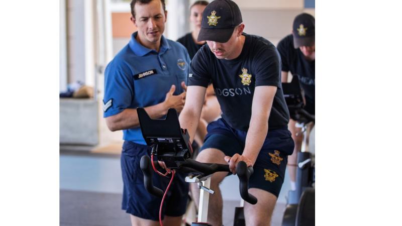 Corporal Matthew Johnson watches over a recruit trialing the new fitness test standard Wattbike at RAAF Base Wagga, NSW.