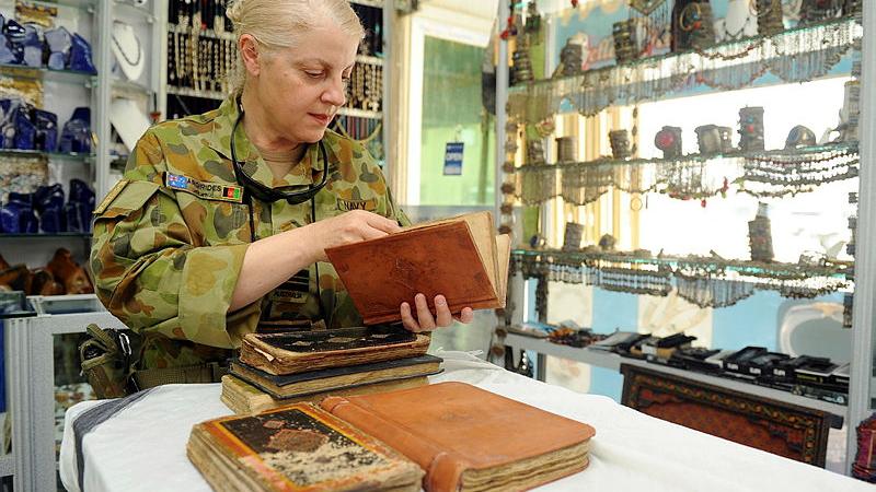 Lieutenant Commander Andrea Argirides inspects antique books from a local shop at Kabul International Airport. 