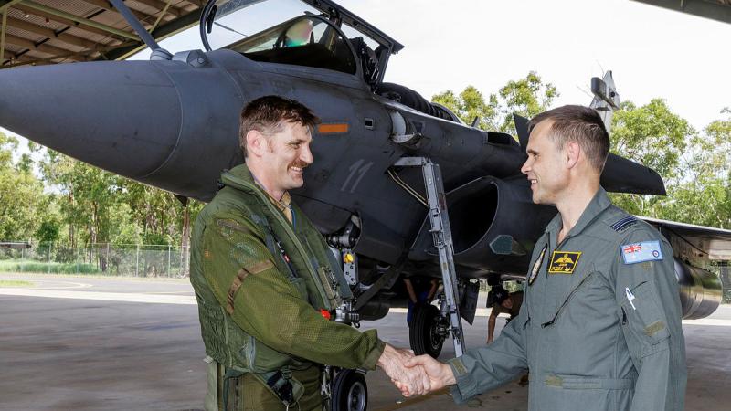 French Navy Detachment Commander Rémi and Royal Australian Air Force Detachment Commander Squadron Leader Jordon Sander shake hands in front of a French fighter jet at RAAF Base Darwin.r Exercise Rastaban 25.