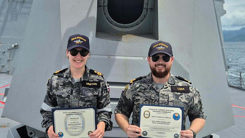 Sub-Lieutenant Mollie Murton and Sub-Lieutenant James Lara stand on the deck of HMAS Brisbane holding certificates for completing advanced Anti-Submarine Warfare training with the US Navy. 