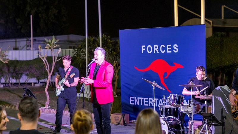 Phil Burton, centre in pink jacket, and band perform at Camp Baird Headquarters Middle East for deployed Australian Defence Force personnel on Australia Day during the Forces Entertainment Tour.
