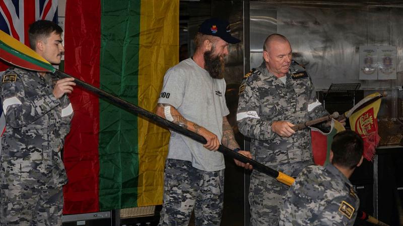 Commanding Officer HMAS Choules, Commander Arron Convery, presents Lithuanian solo adventurer Aurimas Mockus with an oar and national flags salvaged from his vessel after the rescue. 