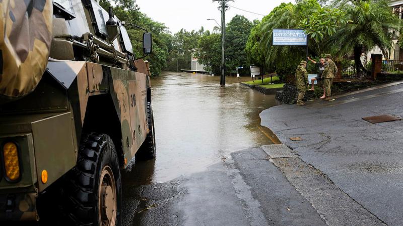 Sergeant Paul Dennis, left, and Lieutenant Jack Macklan talk to Lismore resident Mr Chris McNamara near the flooded Wilsons River during a joint patrol to monitor floodwaters as part of Operation Topical Cyclone Alfred Assist. 