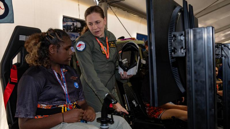 Pilot Officer Daneeka Croker, from No. 1 Flying Training School, instructs a Defence Work Experience Program participant how to operate a flying simulator at the Australian International Airshow 2025. Photo: Leading Aircraftman Campbell Latch