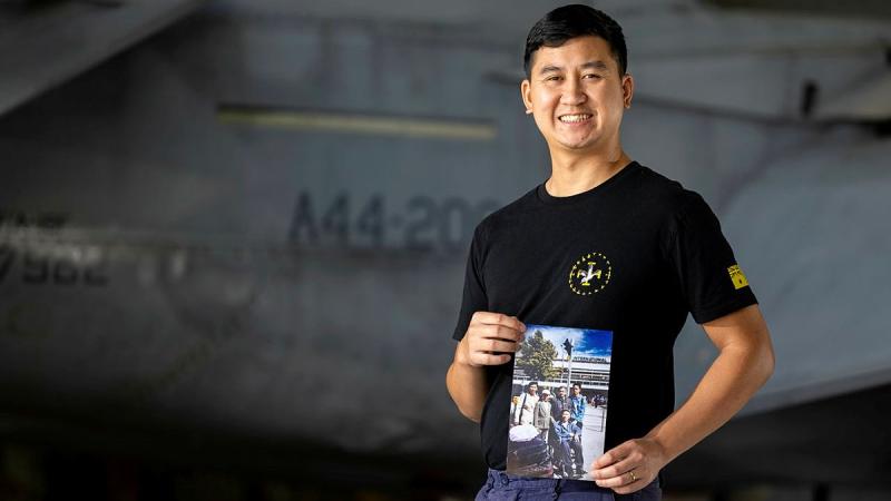 Royal Australian Air Force aviator Corporal Trung Phan, an aircraft structural technician from 1 Squadron at RAAF Base Amberley, holds a photograph of his family on the day they arrived in Australia.
