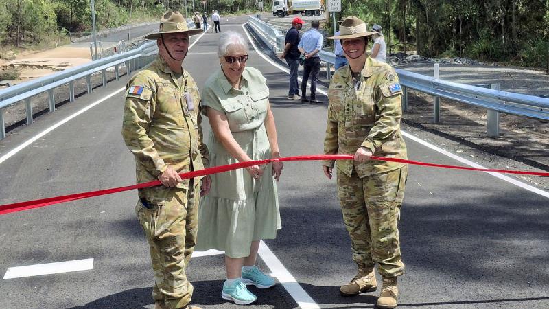 Warrant Officer Class Two Greg Mills, Private Jacinta Watson's mother Genia Otuszewski, and Lieutenant Colonel Rachael Ayoub cut the ribbon to mark the opening of the Private Jacinta Watson Bridge at Greenbank Training Area. 