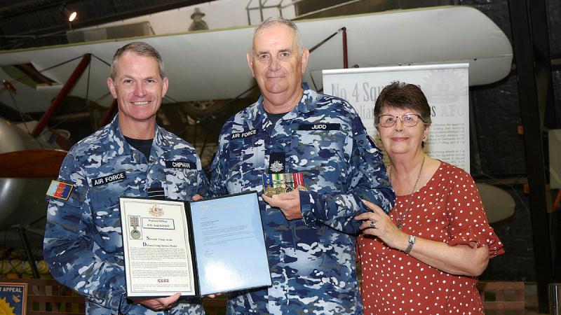 Warrant Officer Richard Judd (centre) alongside his wife Denise, is presented with the Defence Long Service Medal representing 50 years of service by Vice Chief of the Defence Force, Air Marshal Robert Chipman (left) during a ceremony held at the Williamtown Aviation Heritage Centre, NSW. 