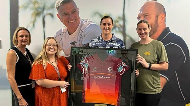 Corporal Sarah Munro, centre, and Private Cassandra Lally, right, from the South East Queensland Netball Association, present staff from Mates4Mates Brisbane a framed jersey to recognise their sponsorship. 