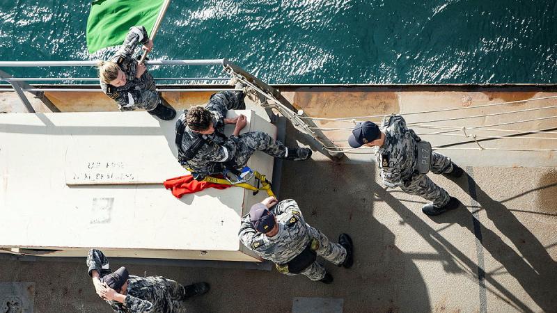 Personnel from the boatswain team on board HMAS Choules stand by to recover a seaboat. 