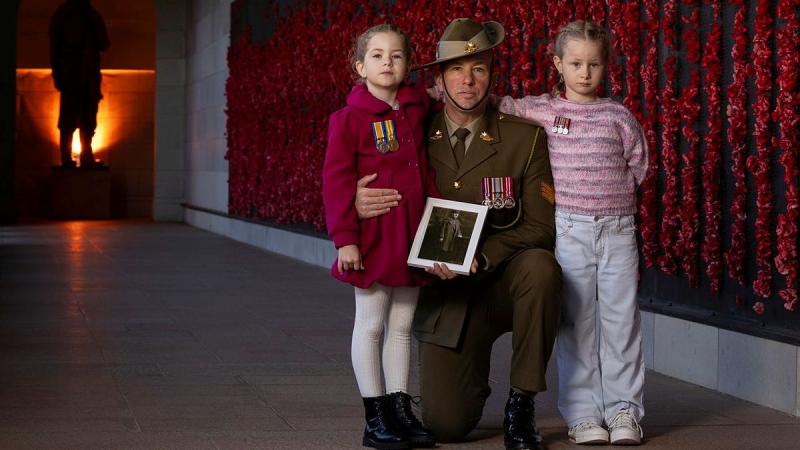 Australian Army soldier Sergeant Jonathan Apps from Australia's Federation Guard with his daughters and a picture of his great-grandfather at the Australian War Memorial in Canberra during preparations for Anzac Day 2025.