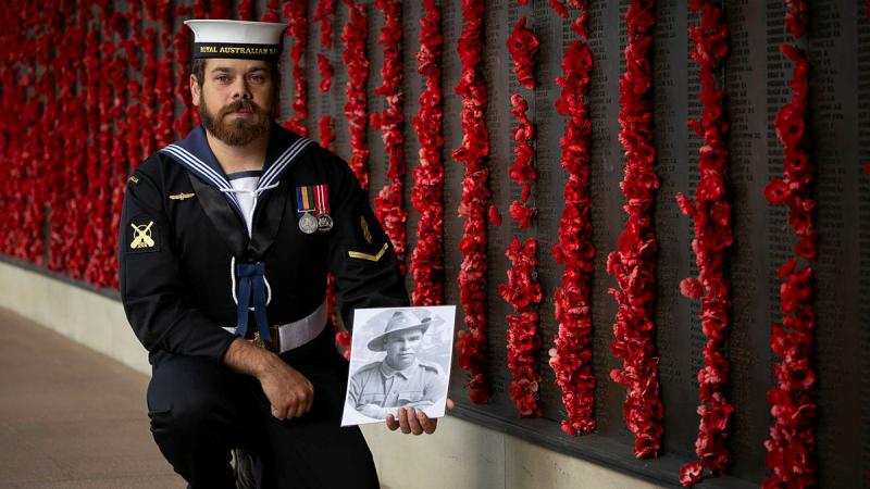 Able Seaman Boatswains Mate Mitchell Rigney holds a photo of his family member Private Arthur Thomas Walker at the Australian War Memorial in Canberra. 