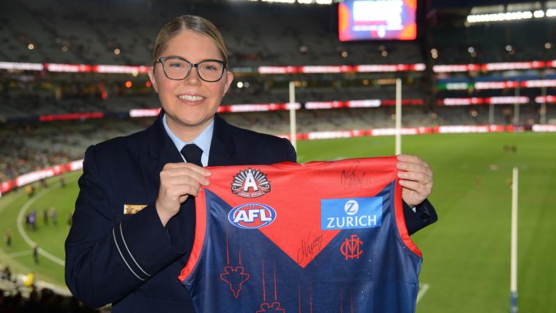 Flight Lieutenant Aimee McCartney with the Melbourne Football Club guernsey that features her F-35A-inspired artwork, at the Melbourne Cricket Ground.