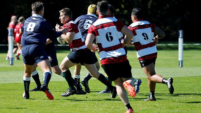 Australian Army Leopards player Warrant Officer Class 2 Zane Mitchell runs with the ball towards two Royal Australian Navy Old Salts players during the ADF Rugby Union Championships. 
