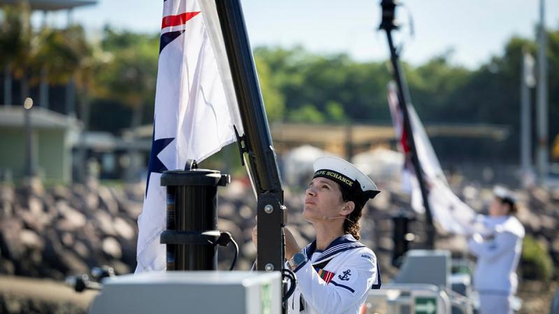 Leading Seaman Communications and Information Systems Teagan Hankins raises the Australian White Ensign for the first time onboard newly Commissioned HMAS Cape Schanck during a ceremony held at HMAS Coonawarra, Darwin, Northern Territory. 