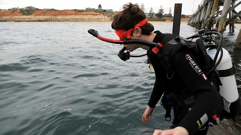 Patrick Killen enters the water from Port Noarlunga Jetty as part of the Veterans Dive Initiative open water course.