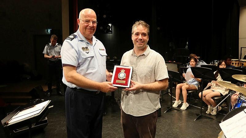Warrant Officer Ben van den Akker, of the Royal Australian Air Force Band, presents a commemorative plaque to Scott Harbin, school band director, during a music workshop and cultural exchange at the United Nations International School in Hanoi, Vietnam. 