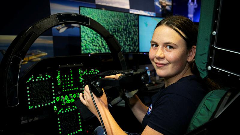 A participant on the Air Force Aviation Program for Women experiences a flight in an F/A-18 simulator at Fighter World during their tour of RAAF Base Williamtown. 