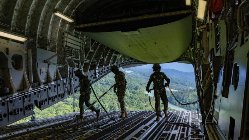 USAF Senior Airman Aniel Reina, RAF Sergeant Iain Blears and RAAF Corporal Jake Willington, on the ramp of a C-17A Globemaster III over Papua New Guinea  for Exercise Global Dexterity 25-1. 