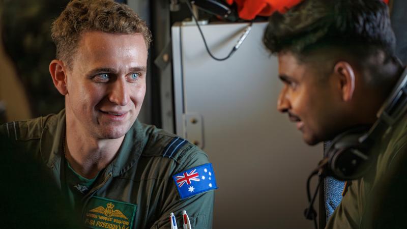Royal Australian Air Force Flight Lieutenant Lawson Woolford chats with Royal Malaysian Air Force Observer, Captain Santos about the characteristics of the P-8A Poseidon during a sortie on Operation Gateway 25-1/2.