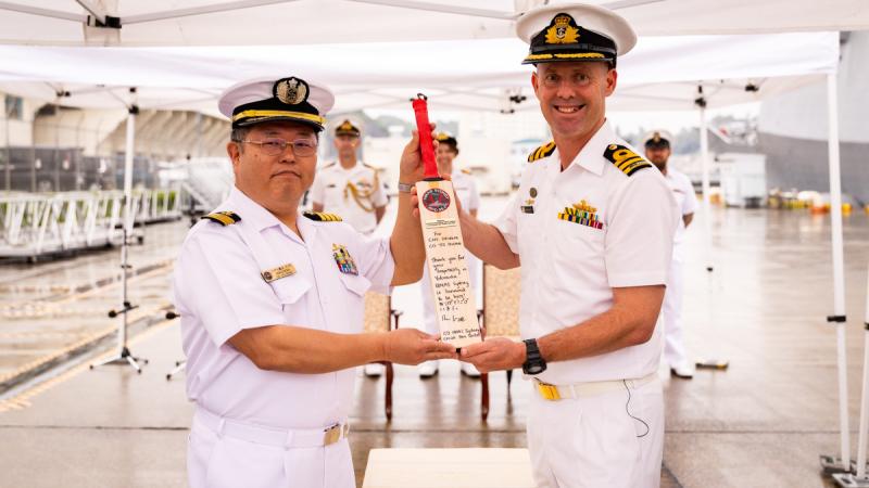 Japanese Maritime Self Defense Force Captain Ishidera Takahiko receives a personalised cricket bat from Commanding Officer HMAS Sydney, Commander Ben Weller, on arrival in Yokosuka during Regional Presence Deployment 25-2.