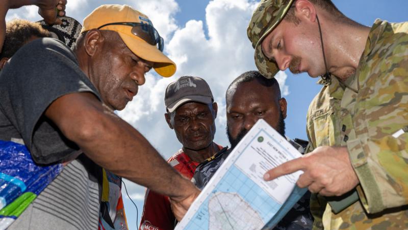 Australian Army officer Captain Steven Smith and Papua New Guinea Defence Force officer Lieutenant Henri Beri review a map with local residents during a visit to reported unexploded ordnance sites in Rabaul, East New Britain. 