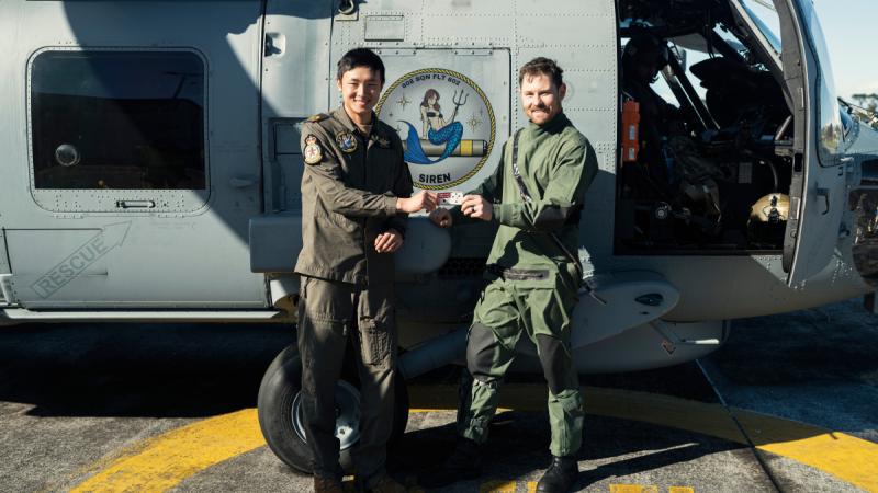 Royal Australian Navy pilot Lieutenant Joel Bulley trades patches with Sub-Lieutenant Walkie Wang during a visit to New Zealand Defence Force 6 Squadron in Auckland. 