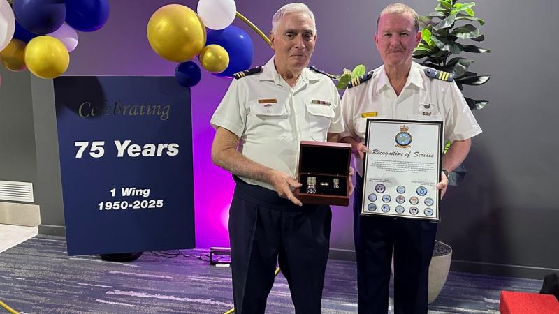 Wing Commander (AAFC) Ken Whelan presents Squadron Leader (AAFC) Geoff Strange a recognition of service certificate and ninth clasp to his Defence Long Service Medal..