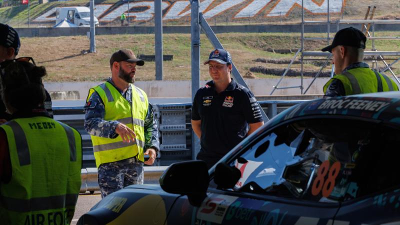 Sergeant Greg Shields, a 13 Squadron ground support equipment technician, speaks with a Red Bull Racing V8 Supercar mechanic in the pits at Hidden Valley Raceway. 