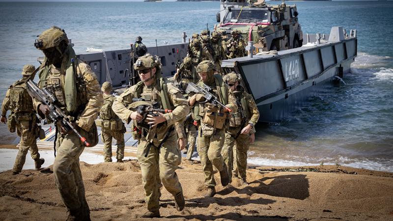 Australian Army soldiers departing a Royal Australian Navy Light Landing Craft on the Beach. 