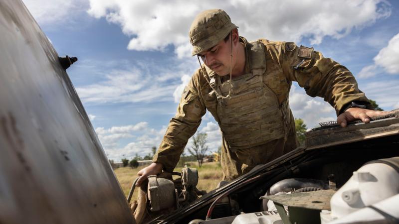 Army vehicle technician Corporal Jacob Sofia, from 2nd Cavalry Regiment, inspects the engine of an Australian Light Armoured Vehicle during Exercise Eagle March at the Townsville Field Training Area.