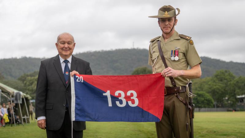 Battery Commander, Major Andrew Penhaligon, of 20th Regiment, Royal Australian Artillery, receives the 133rd Battery flag from former battery commander, Major Allan Harrison (Retired), during the 'Locating Artillery' centenary parade at Gallipoli Barracks, Enoggera.