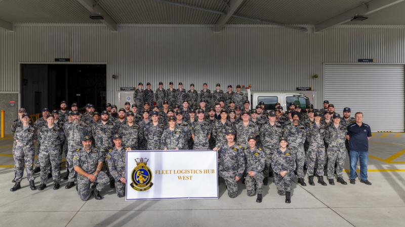 Sailors in a shed for team photograph of Fleet Logistics Hub - West at HMAS Stirling, Western Australia.