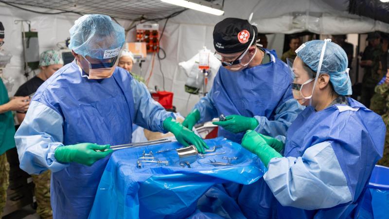 Medical staff examine medical instruments in a field tent.