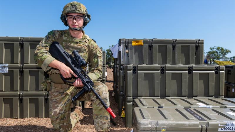 An Australian Army male soldier takes a knee with his rifle with helmet and body armour. 