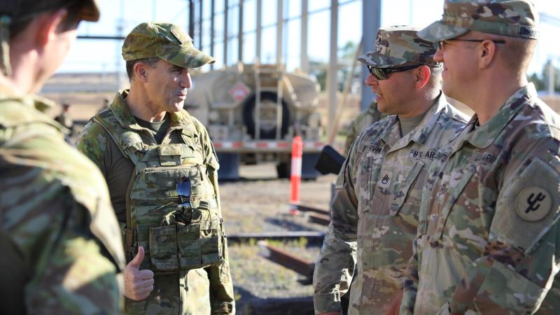 Soldiers from Australia and the US standing and talking to each other.