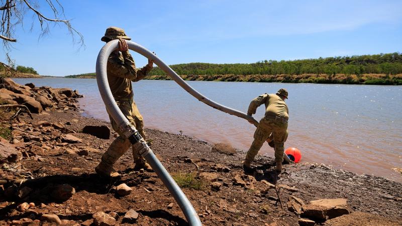 Soldiers extract water for desalination and purification from a river.